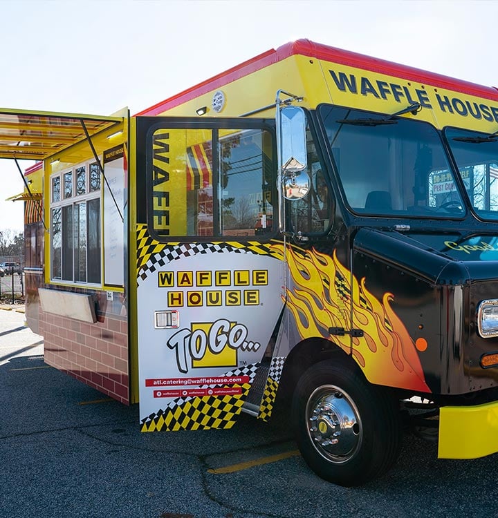 Young couple posing for wedding photos in front of Waffle House food truck