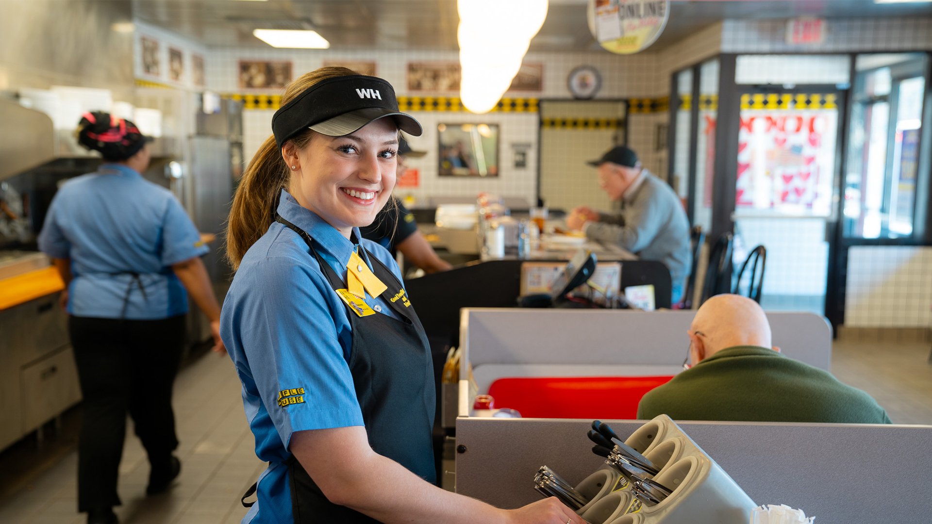 Smiling Waffle House employee grabbing silverware